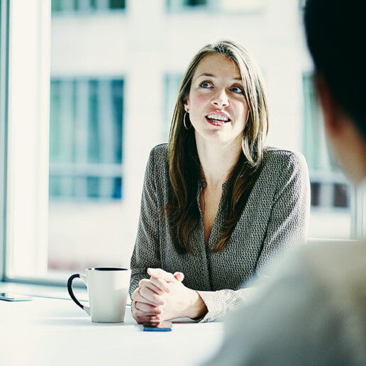 Business professional engaged in a discussion during a team meeting in a modern office, representing leadership, collaboration, and strategic communication.