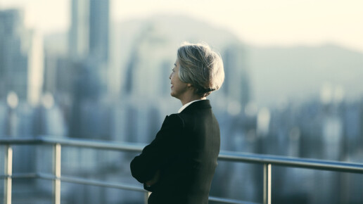 Business professional looking out over a city skyline, reflecting on strategic decisions.