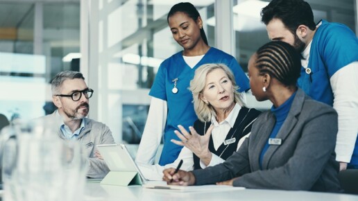 Health care leaders and clinicians discussing strategy around a conference table.